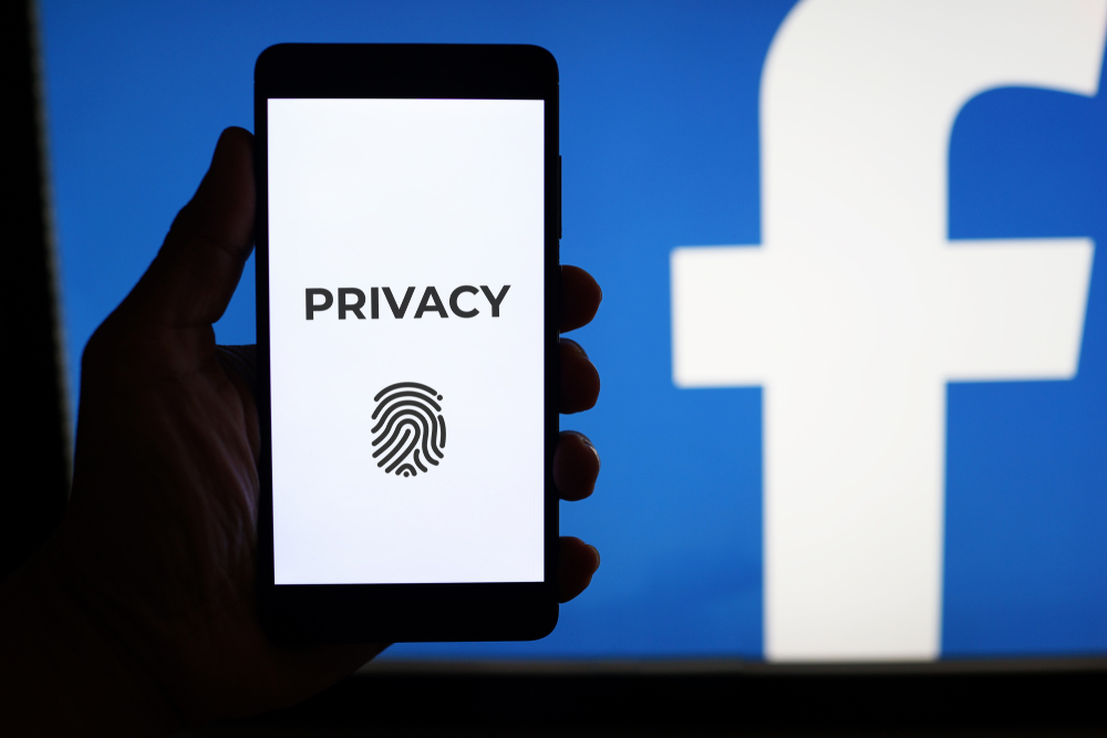 Facebook-Logo mit einem Handy auf welchem Privatsphäre vermerkt ist